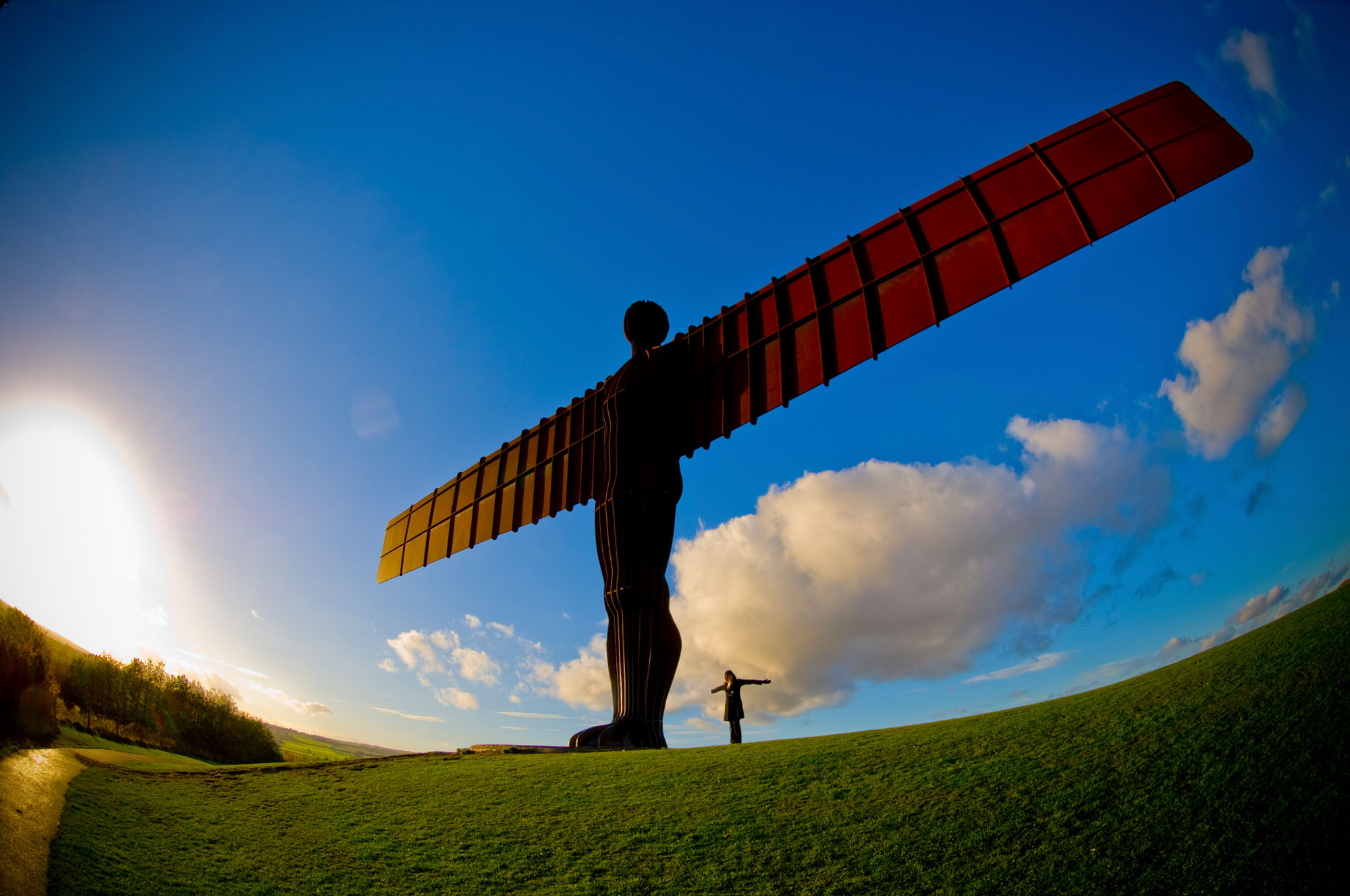 Person standing next to the Angel of the North statue to demonstrate scale.